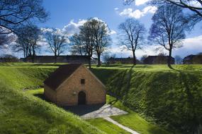 Brick house, among the beautiful, green fields and trees, under the blue sky with clouds