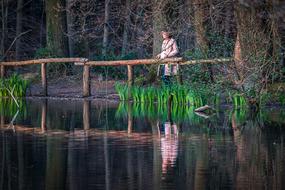Girl near the beautiful lake with green grass and trees