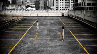 People, standing on the court with yellow marks, among the buildings in black and white colors