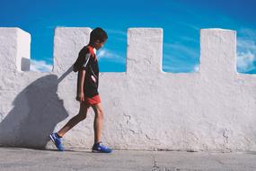 sportive child boy walking at stone wall