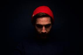 Man in red hat looking down at darkness
