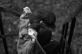 person in cap sits outdoor on a blurred background