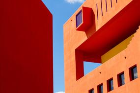 Orange buildings with windows in light at blue sky with white clouds on background