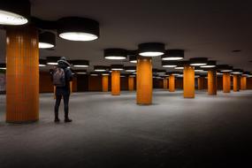 Man, walking in the building with orange columns, in lights