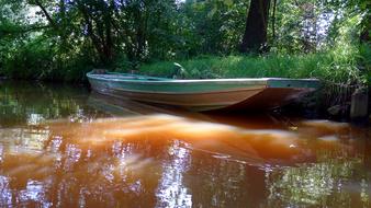 boat moored on brown Water in forest, summer Landscape