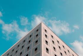 Corner of the building in shadow and sunlight, under the blue sky with white clouds