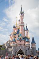 Beautiful and colorful castle in the Disneyland Park in Paris, France, in light, under the blue sky with clouds