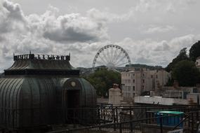 Ferris wheel and buildings, under the cloudy sky, in England, in black and white colours