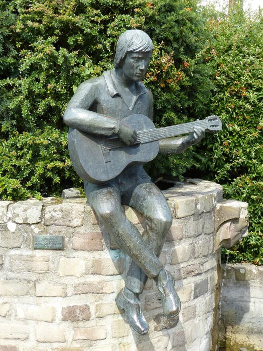 young man plays Guitar, sculpture on brick wall