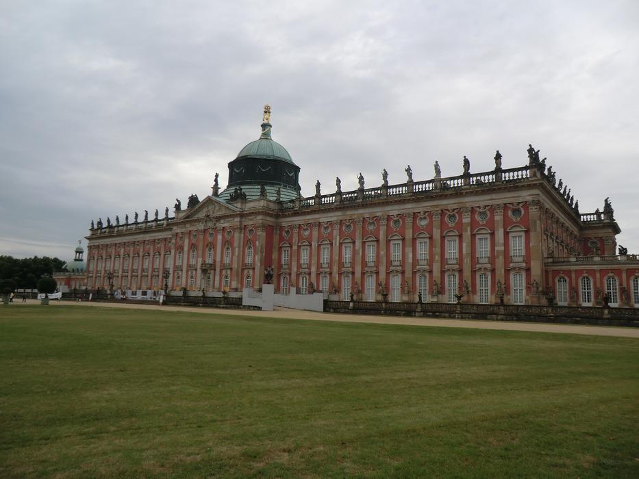 Beautiful and colorful Sanssouci, with the green meadow, among the green trees, in Potsdam, Germany, under the clouds