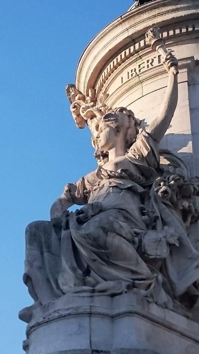 Beautiful sculpture on the ornamental fountain, in light and shadow, in Paris, France, under the blue sky