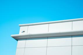Corner of the white building, in sunlight, under the blue sky