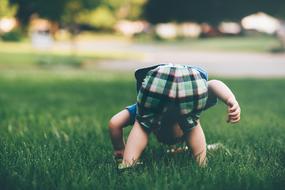 child stands leaning on the lawn