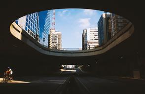 Person, cycling on the bicycle in the tunnel, with the city view, with the buildings