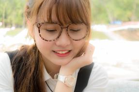 Portrait of the smiling, pretty girl with glasses and wrist watch