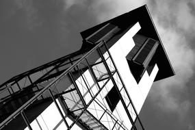 Black and white photo of the lighthouse, in light and shadow, under the sky with clouds