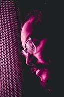 Male face in eyeglasses at purple light