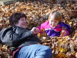 Mother with the girl child on the colorful dry leaves