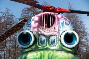 Colorful , painted helicopter with the graffiti, near the trees, under the blue sky