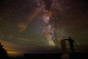 man stands beneath gorgeous starry sky