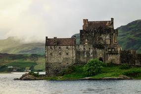 castle on a hill on the bank of a pond