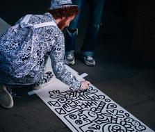 young man painting pattern on pavement