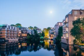 Beautiful landscape of the canal, among the colorful buildings, with the reflections, among the plants, under the blue sky with clouds