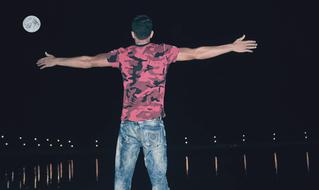 Man in front of water at full moon night