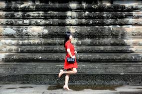 photo of a girl in a red dress on a background of a burnt wall