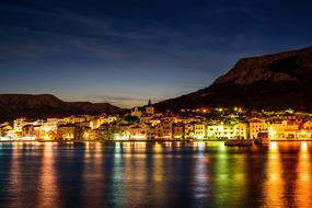 multicolored night city lights are reflected in the sea