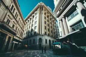 People, on the street, among the buildings, in shadows and sunlight, under the blue sky