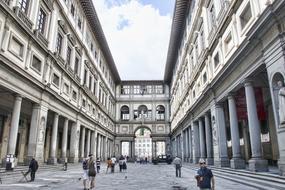 People, among the beautiful architecture, with the columns in Florence, Tuscany, Italy, under the blue sky with white clouds