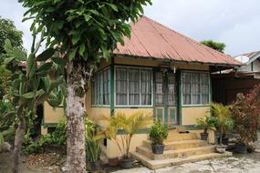 Colorful, old house, among the colorful plants, under the cloudy sky, on the landscape on Samosir, Indonesia