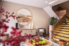 Beautiful, round painting and colorful plants in the living room, with the staircase