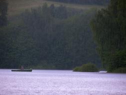 distant view of the boat on the lake in the forest in the rain