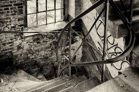 Black and white photo of the stairs with the railing, in the old building, with the window