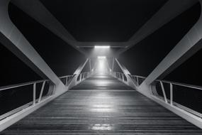 Black and white photo of the bridge, in lights, among the darkness