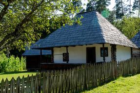 Traditional romanian farmhouse behind wooden fence at summer