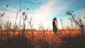Girl on Field behind dry Plants