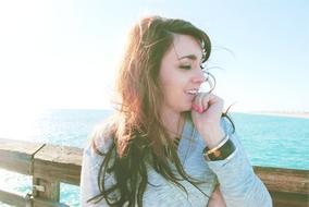 brunette with long hair stands on a wooden bridge