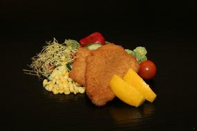 Fish fillet with vegetables on a black background