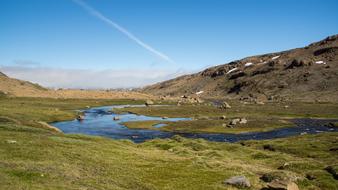 river in a field in the mountains