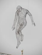 Black and white sculpture of a man made of thread, in the air