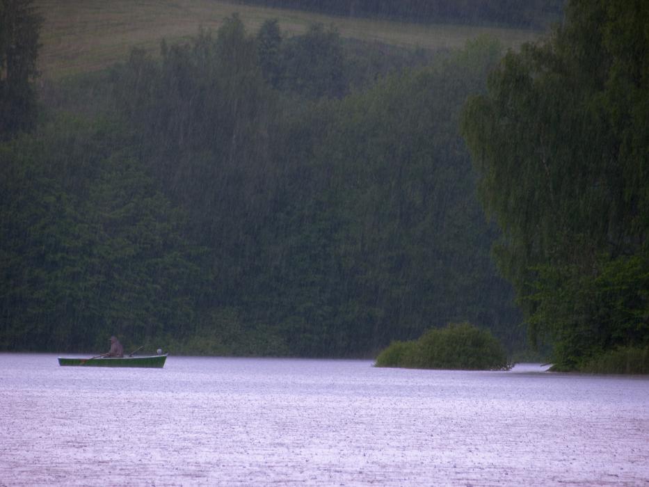 distant view of the boat on the lake in the forest in the rain