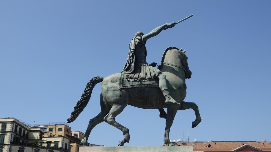 Beautiful, green monument of the Roman Emperor on the horse, among the buildings, under the blue sky