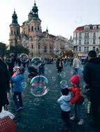 People, among the flying, colorful bubbles, in the beautiful and colorful old town of Prague, Czech Republic