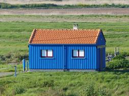 Blue house, with the brown roof, among the meadow, with the beautiful, green grass, in sunlight, in Fort Brouage, Charente, France