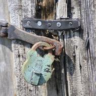 Close-up of the colorful, rustic padlock, on the wooden door, in light