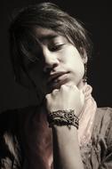 Black and white photo with portrait of the person with bracelet, at dark background