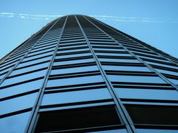 Low angle shot of the shiny skyscraper, under the blue sky with white contrail, in Frankfurt, Germany